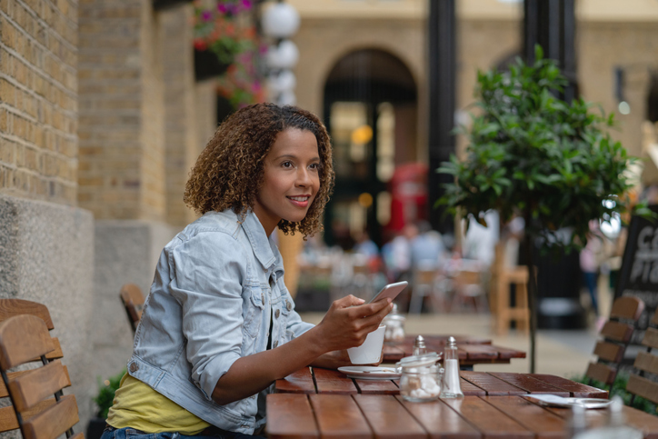 Black woman at a coffee shop using her cell phone