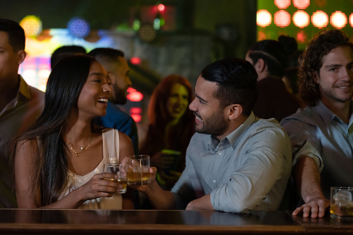 Happy couple drinking at the bar at a nightclub