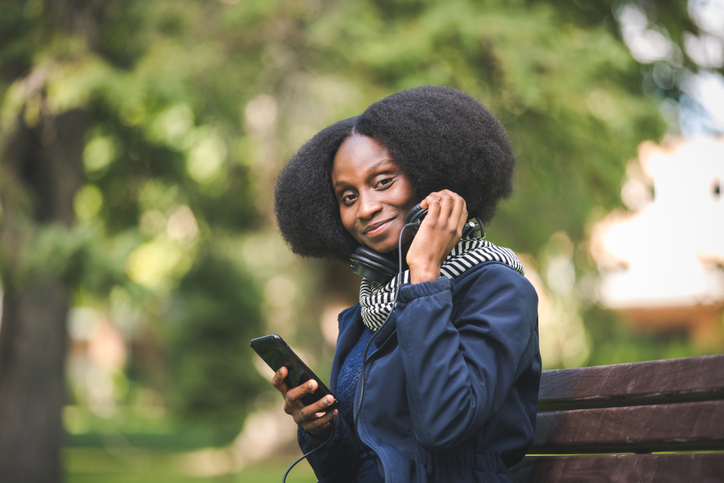 Beautiful African American Woman Getting Ready to Listen To A Podcast On Her Mobile Device, In A Public Park