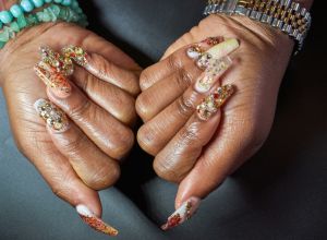 A close-up of a manicured hand and chandelier nails