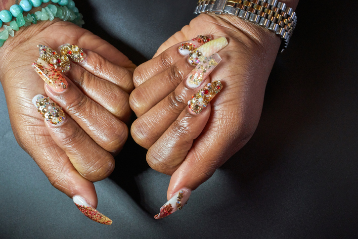 A close-up of a manicured hand and chandelier nails