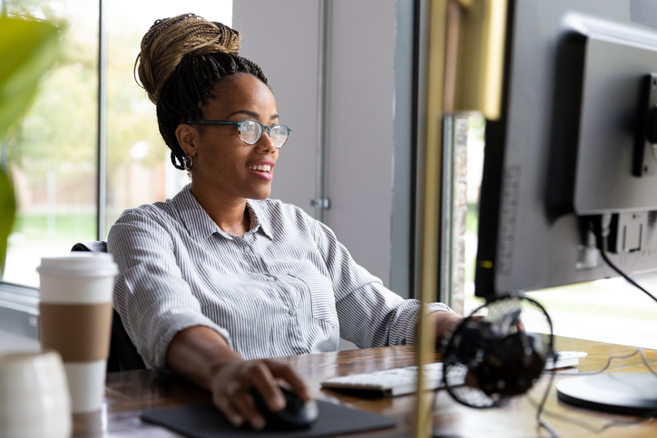 Mid adult female boss smiles as she works at computer