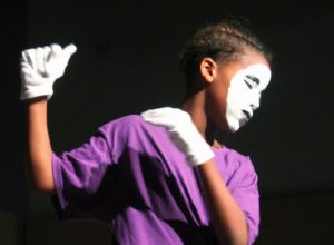 Boy With Painted Face Dancing Against Black Background