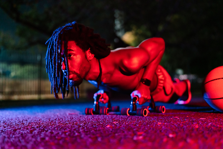 Cool and athletic black man training push-ups at night