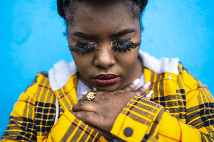 Young african woman standing arms crossed in front of color background