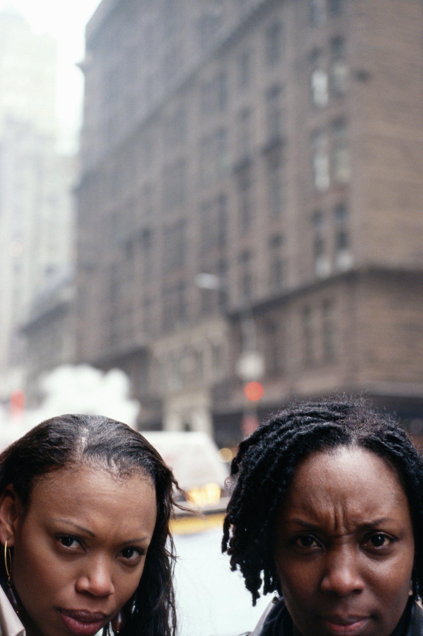 Two women in street, frowning, close-up, portrait
