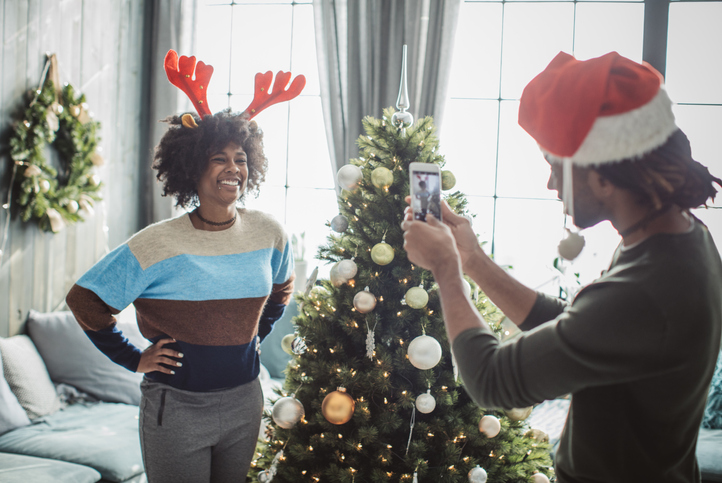 Couple decorating Christmas tree and take photos