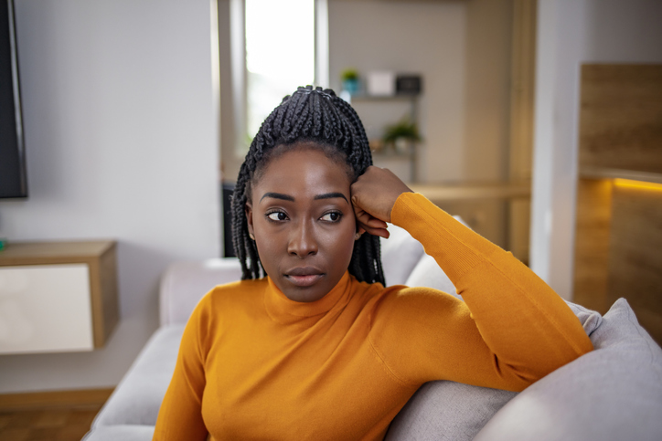 Young attractive and sad black African American woman sitting depressed at home