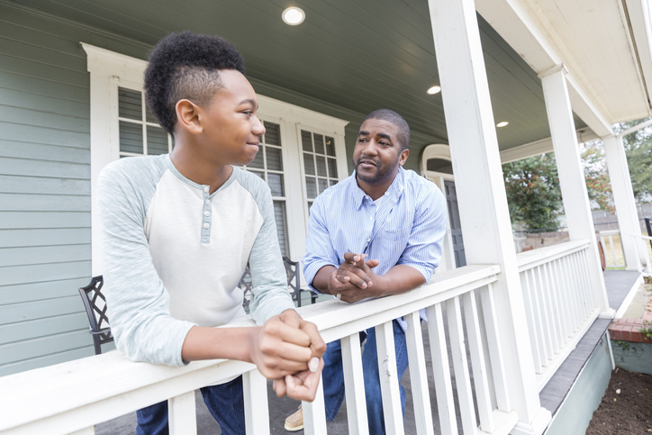 Father and preteen son enjoy time together on front porch