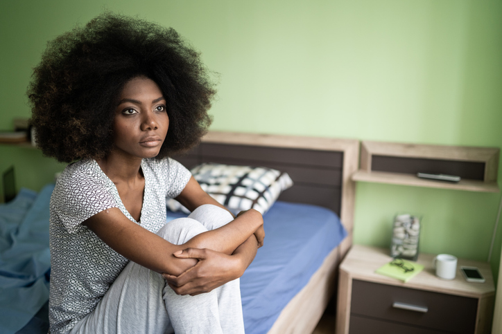 Sad afro woman sitting on a bed