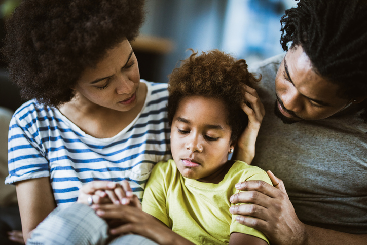 African American parents consoling their sad girl at home.