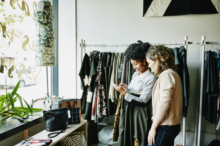 Woman showing shop owner photos on smartphone