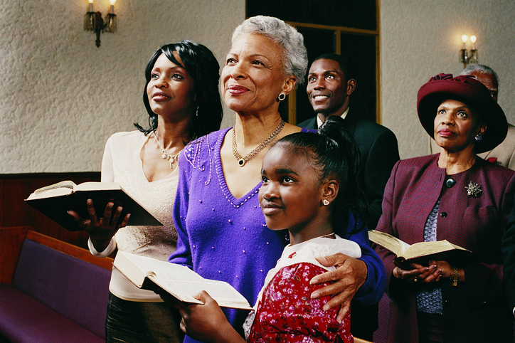 Family Standing in Church Pews Holding Bibles and Listening to a Service