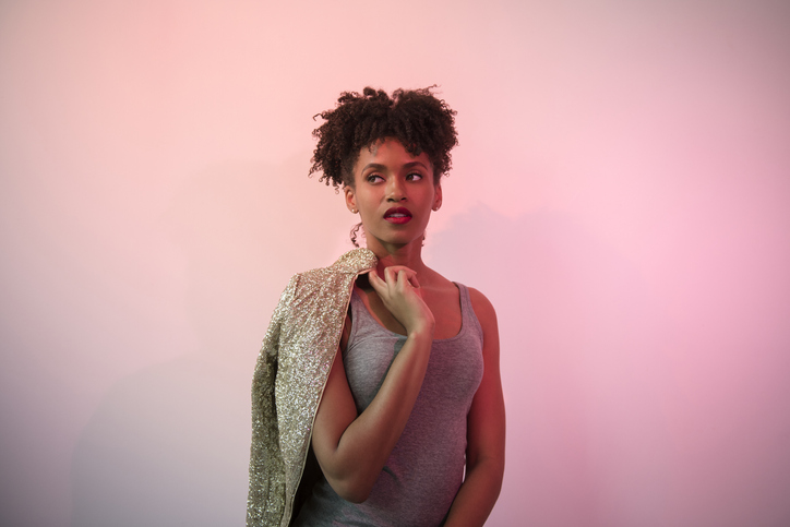 Black woman carrying glamorous jacket on shoulder