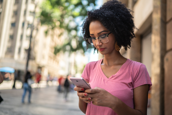 Latinx young woman in the city using smartphone