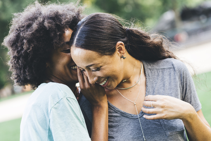 Two young women whispering in a park