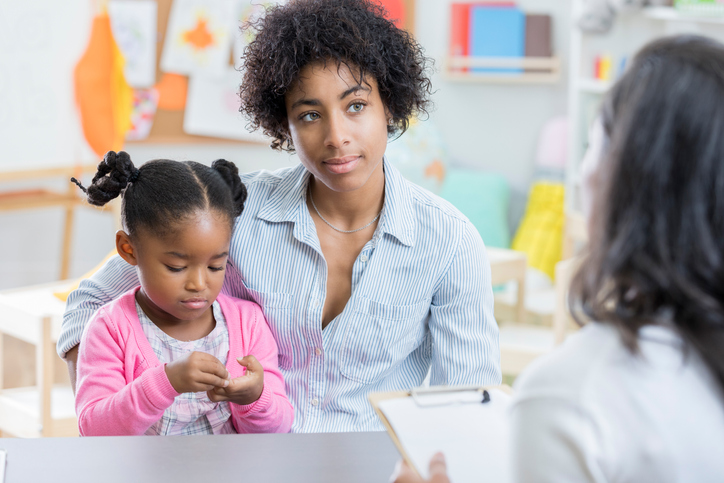 Young mother listens to daughter's preschool evaluation