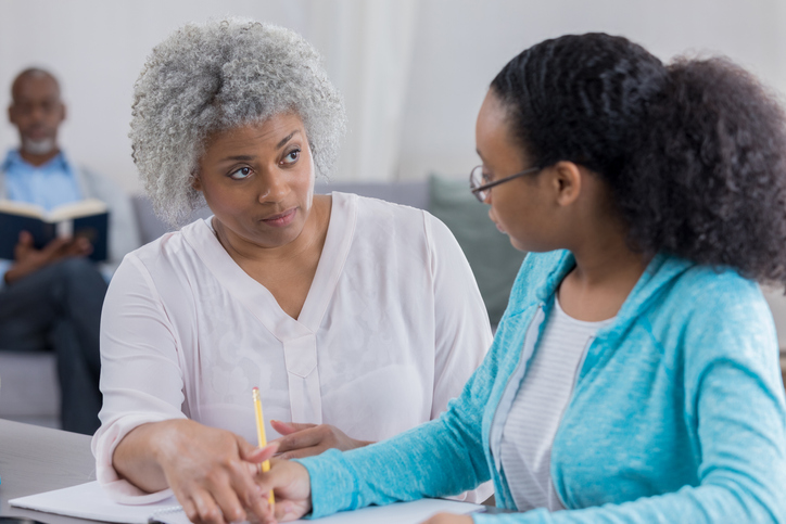 Senior woman disciplines granddaughter regarding homework