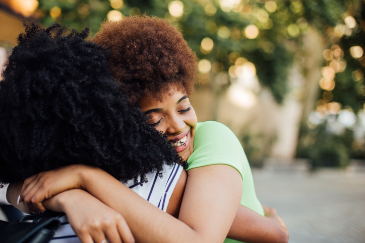 Afro girlfriends embracing on the street