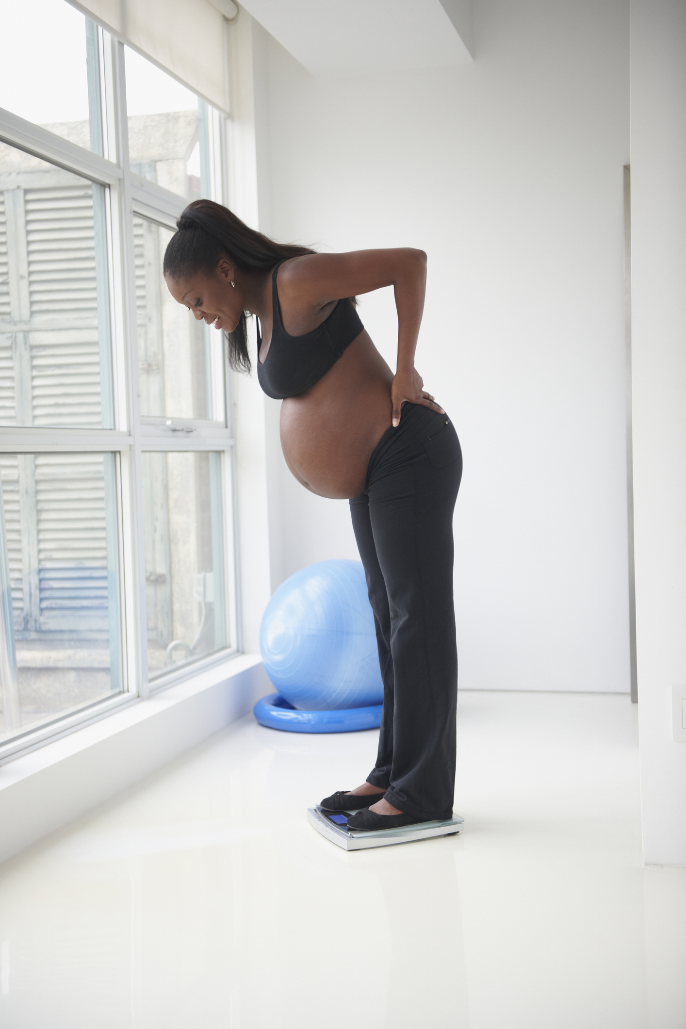 Pregnant Black woman standing on scale