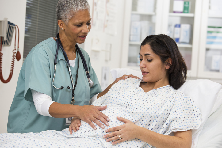 Black doctor examining pregnant patient's belly