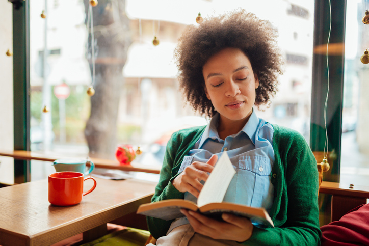 Young woman with curly hairstyle reading a book