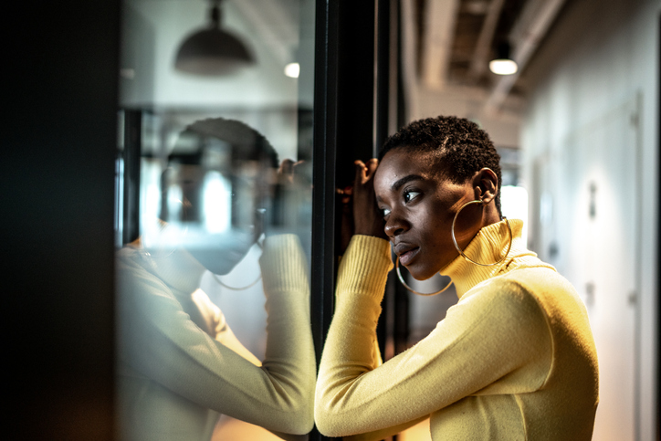 Young businesswoman looking through window at corridor office