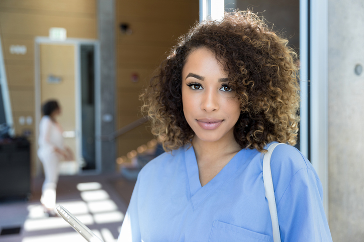 Young female nursing student in scrubs stands outside lecture hall