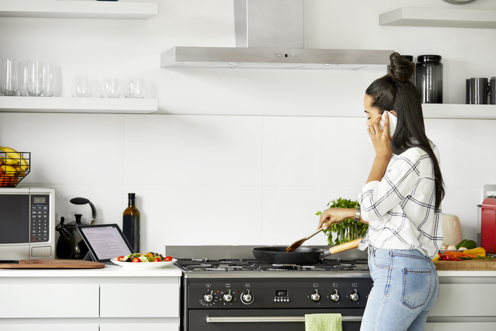 Woman talking on phone while cooking in kitchen
