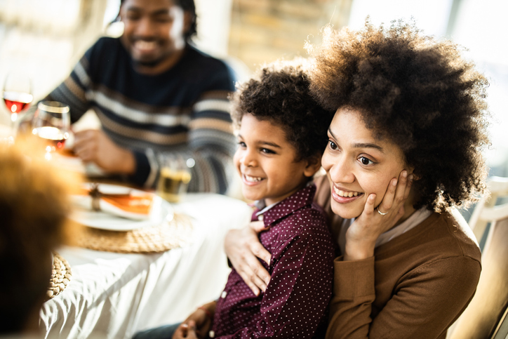 Happy black mother and son during lunch at dining table.