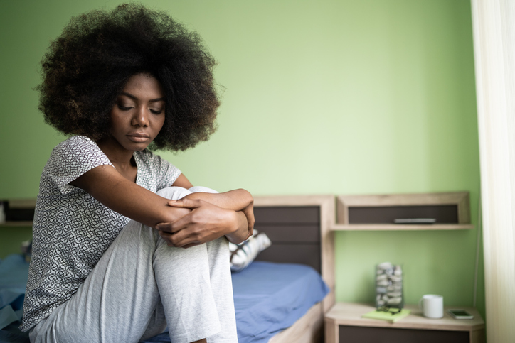 Sad afro woman sitting on a bed