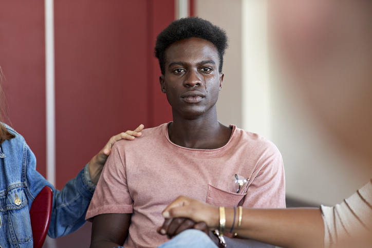 Sad man being consoled by friends in group therapy