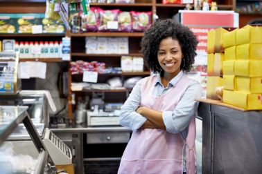 Smiling female cashier with arms crossed at store