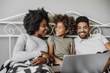 African American family using laptop in bed