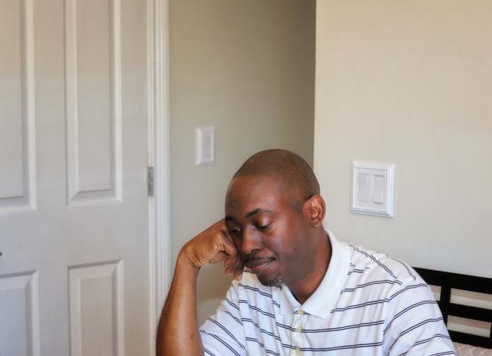 Portrait Of Young Man Sitting Against Wall At Home