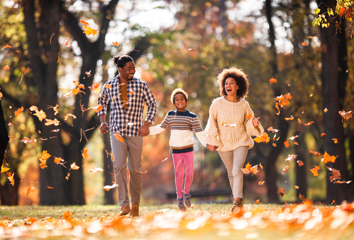 Carefree black family holding hands and running in nature.