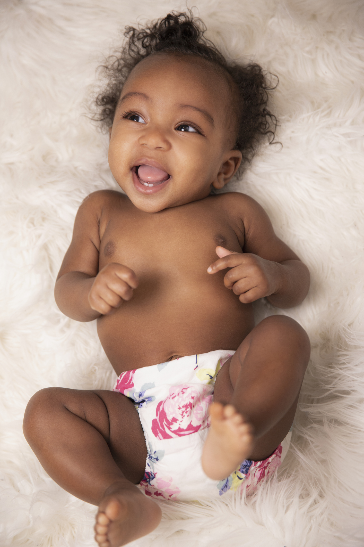 Three month old African American baby girl laying on her back in a diaper