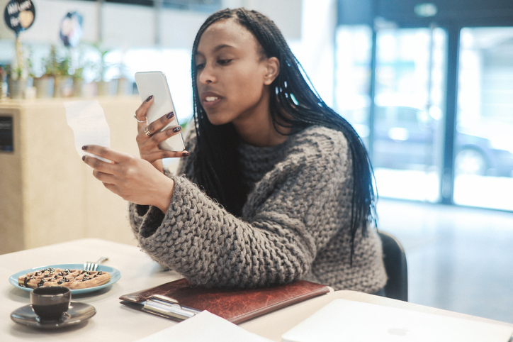 Young woman photographing paper currency in cafe