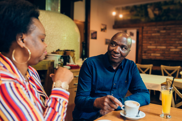 Mature African - American couple enjoying coffee before ordering dinner