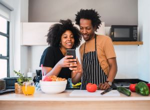 Couple Using Mobile Phone While Standing In Kitchen