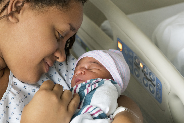 Black mother cradling newborn son in hospital