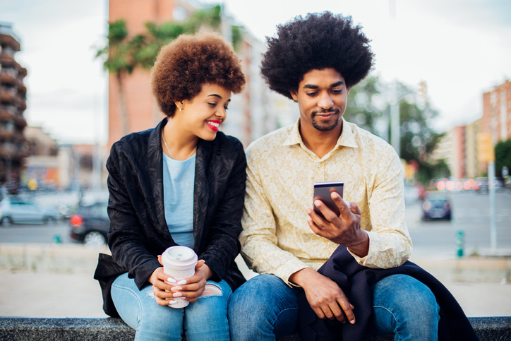 Afro couple using smartphone on the street