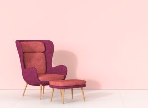 Retro style arm chair and stool against pink wall