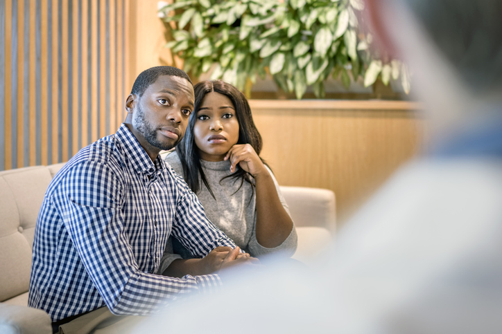 Worried young couple discussing with doctor