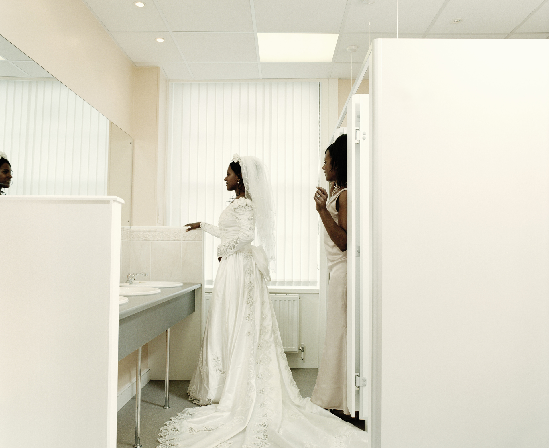 Bride and bridesmaid facing mirror in bathroom