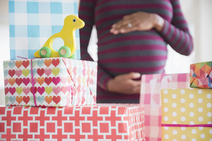 Black pregnant woman admiring gifts at baby shower