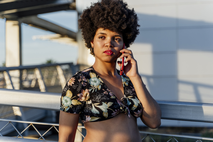 Smiling Afro-American woman with red smartphone