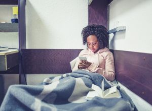 Young African female student , relaxing and listening music in a University campus room
