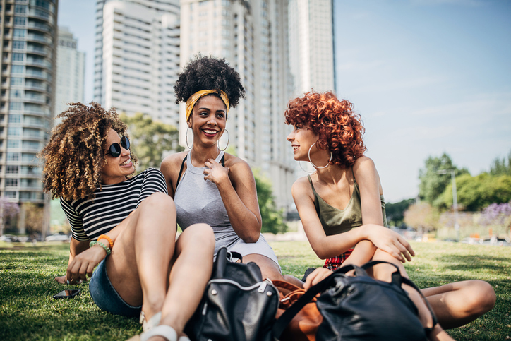 Three beautiful women sitting on grass in park