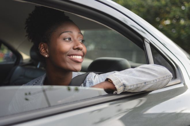 Young afro woman looking out from the car backseat window